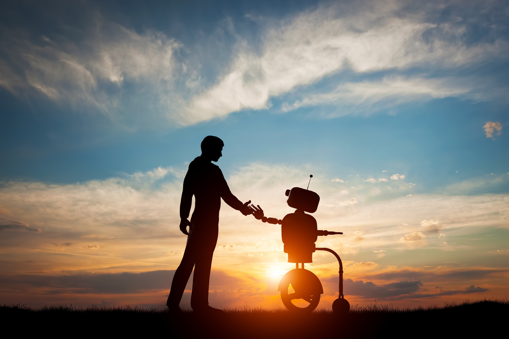 夕日を背景にロボットと握手をする人