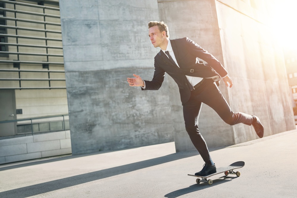 スケートボードに乗って移動するスーツ姿の男性