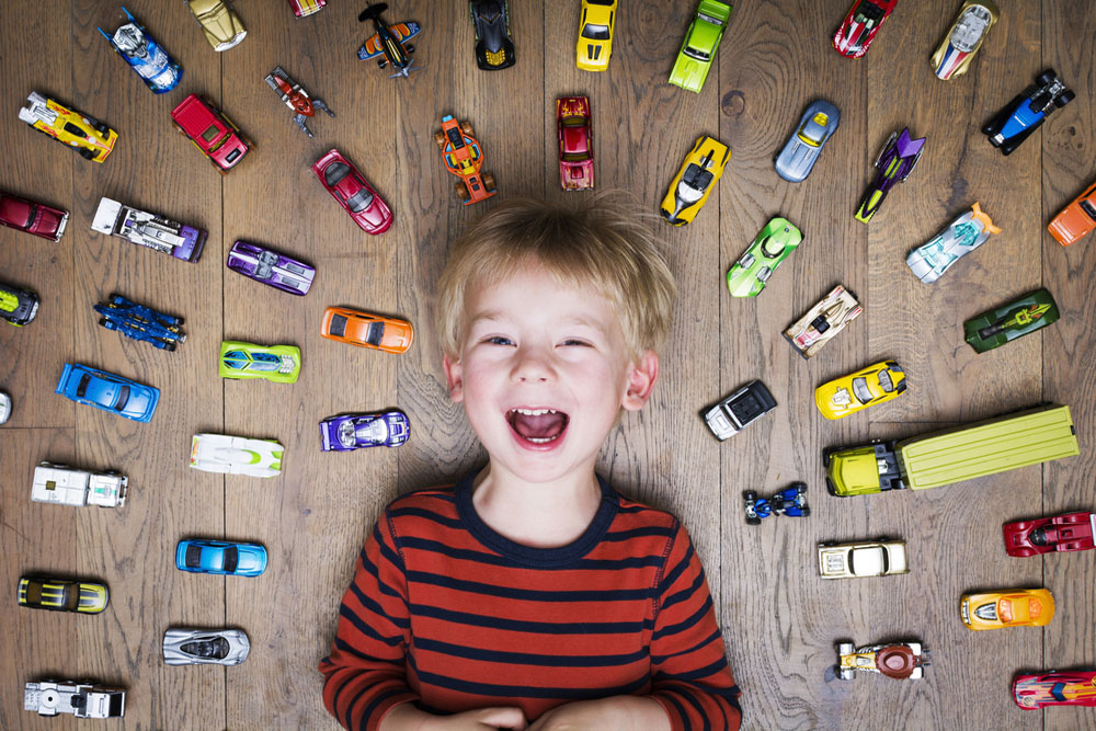 車のおもちゃを並べて喜ぶ子供