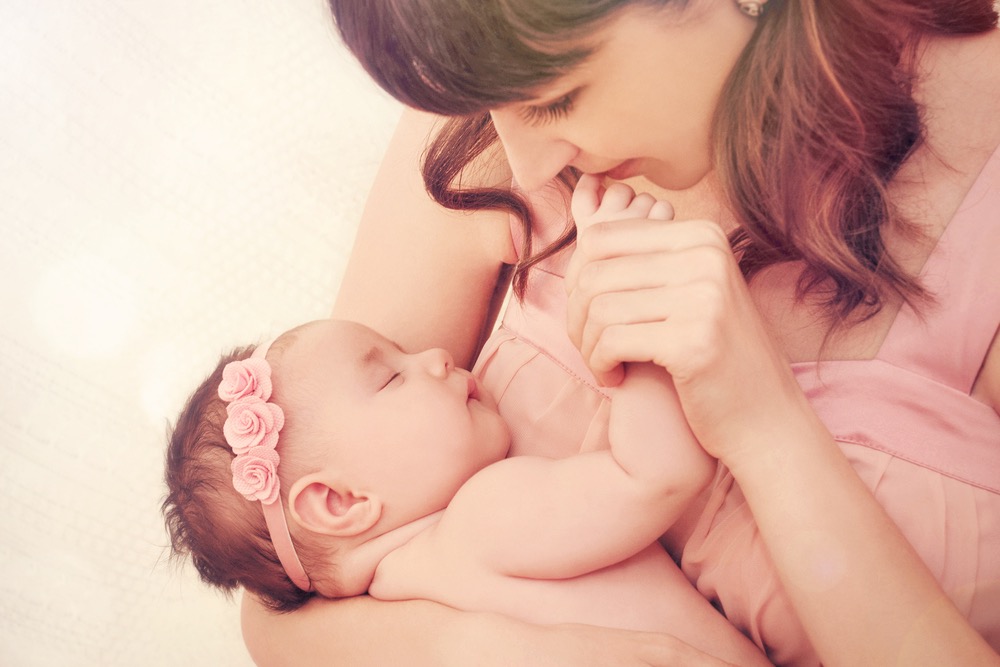 赤ちゃんを抱いて指にキスする女性